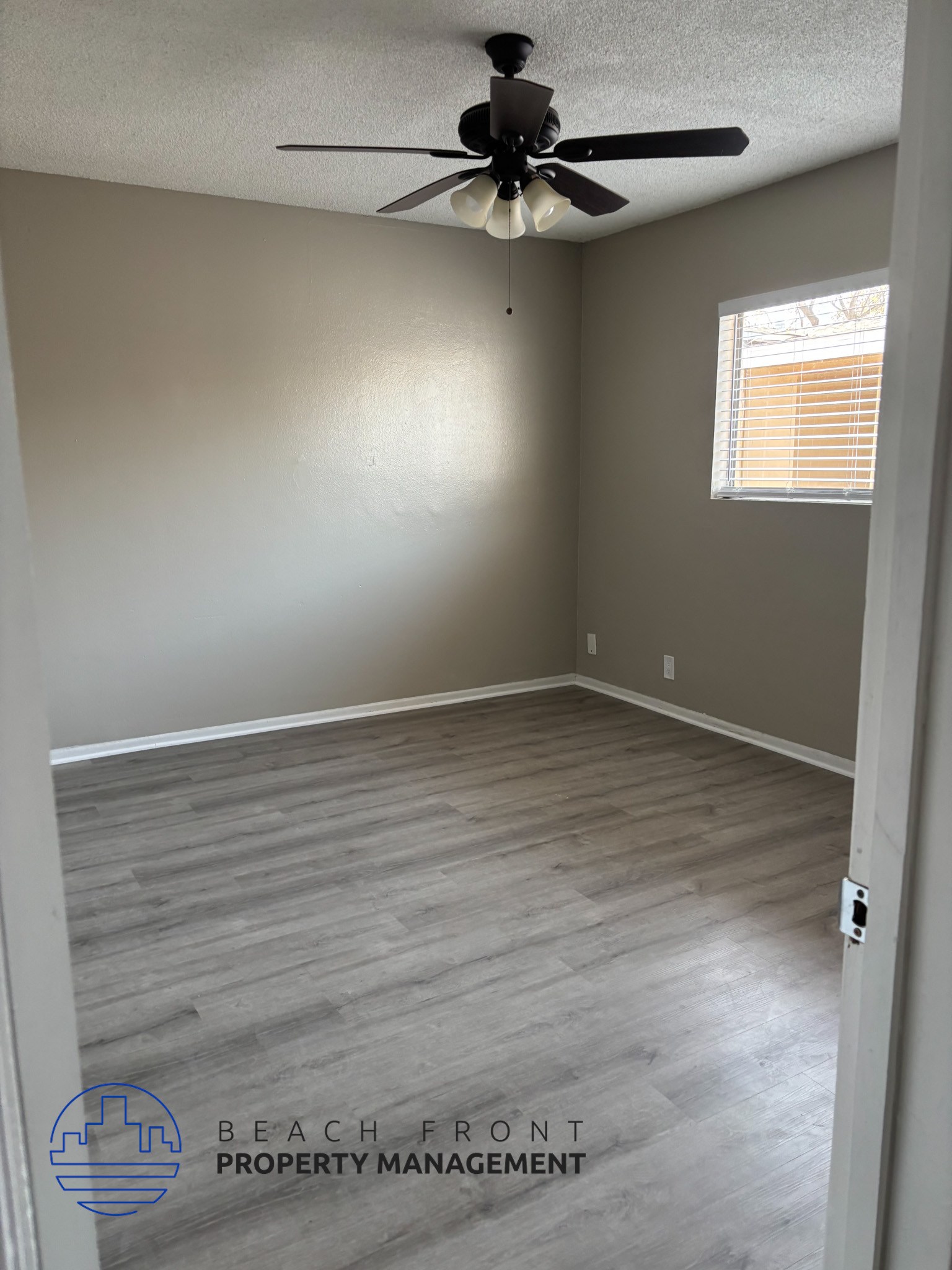 , A room with a ceiling fan and light fixture, wooden flooring, and a window with blinds.,A room with a ceiling fan and light fixture, wooden flooring, and a window with blinds.